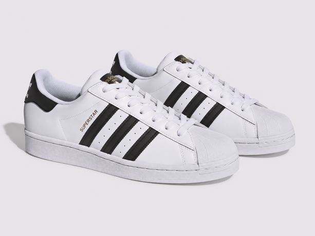 Product photo of a pair of white leather trainers with black stripes on a light grey background