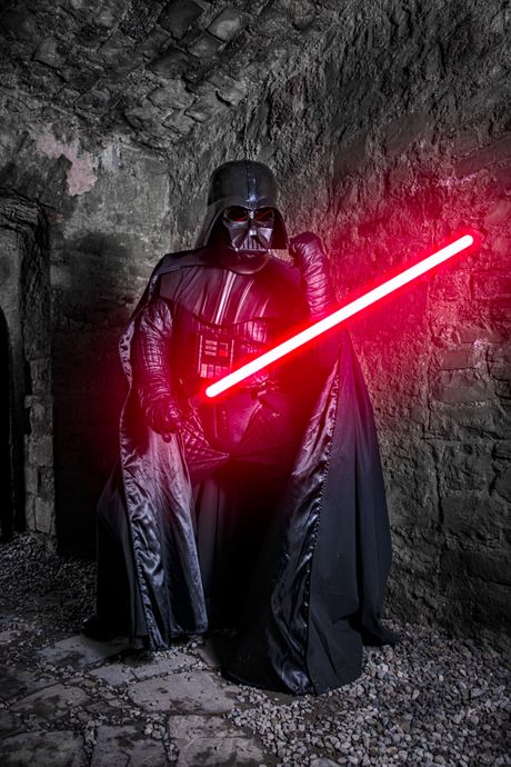 Character photo of a hooded figure in black holding a glowing red blade in a stone ruin