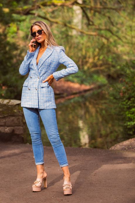 Fashion photo of a woman in a light blue blazer and jeans on a garden path