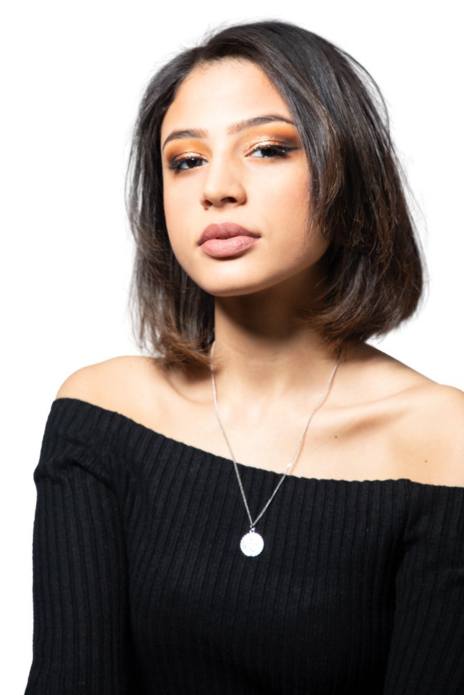 Headshot of a woman with a bob haircut in an off-the-shoulder black top and pendant necklace