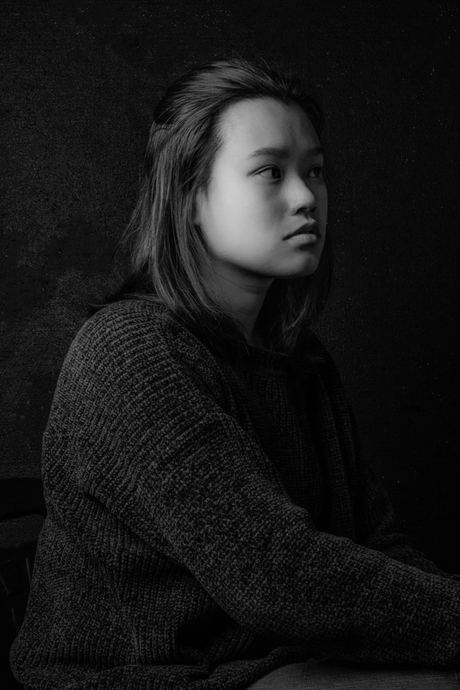 Low-key black and white portrait of a woman in a dark jumper