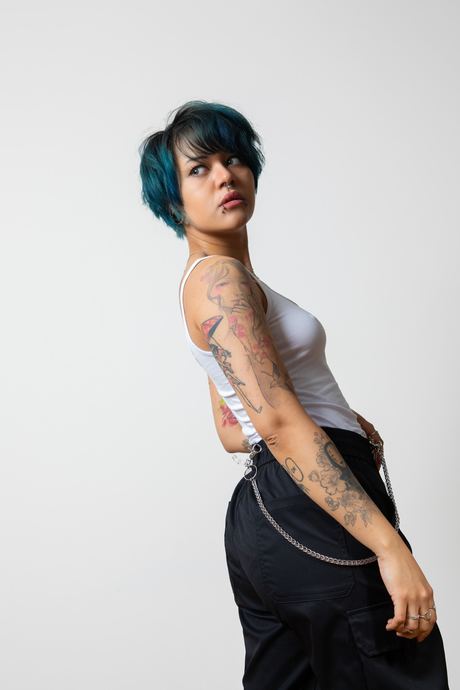 Portrait of a woman with teal hair in a white top on a white background