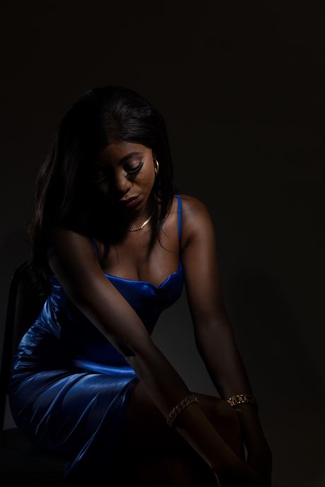 Low-key portrait in deep blue tones of a woman seated in a dark dress