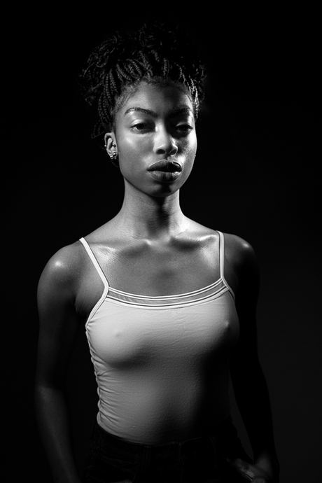 Black and white portrait of a woman in a white vest top on a dark background