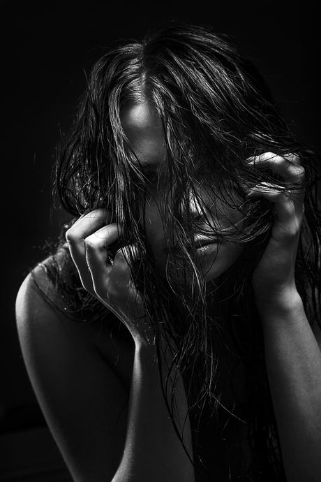 Black and white portrait with wet hair and hands framing the face
