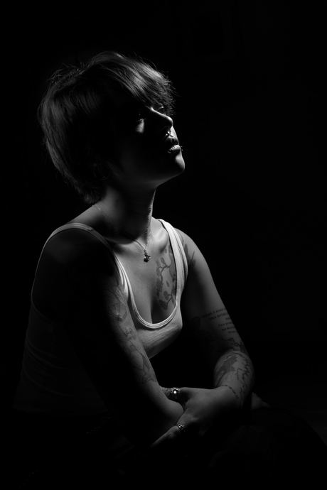 Low-key black and white portrait of a seated figure